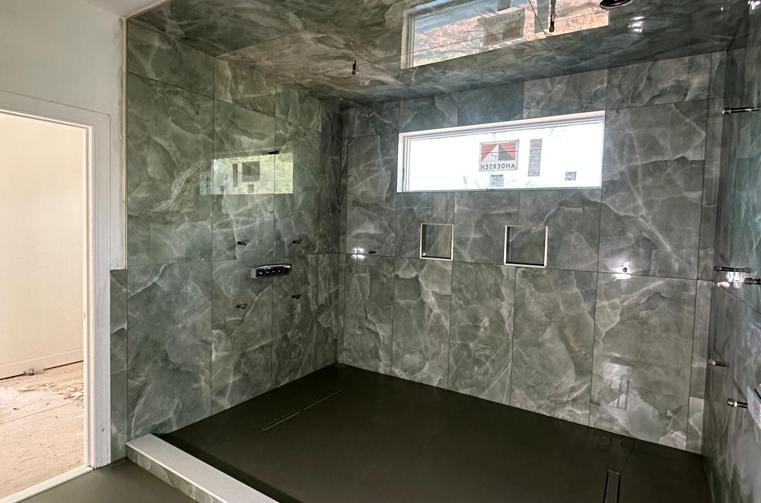 Finished dark green porcelain shower with recessed niche by Silcam Tile