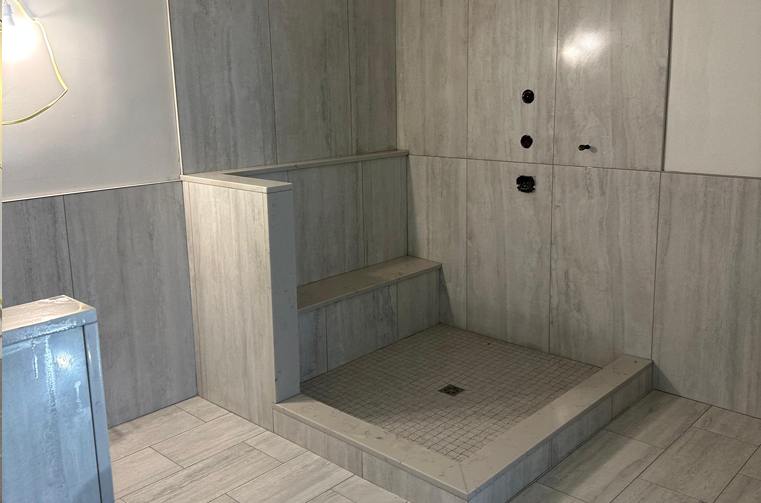Finished grey porcelain shower with tiled bench and step by Silcam Tile